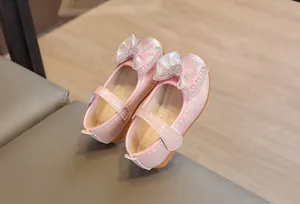 Close-up of pink Mary Jane shoes with woven texture and rhinestone heart bow
