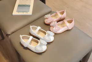 Detail of pink and white Mary Jane shoes for girls featuring large bows and heart gems