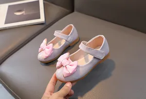 Detail van glanzende paarse Mary Jane-schoenen met roze strik en klittenbandsluiting