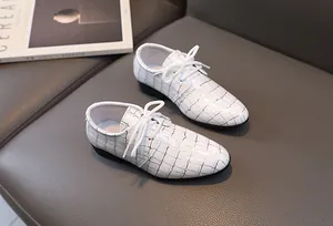 Detail von weißen Jungenschuhen mit goldenem Karomuster und runden Schnürsenkeln