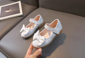 Detailopname van witte Mary Jane meisjesschoenen met satijnen strik en klittenbandsluiting