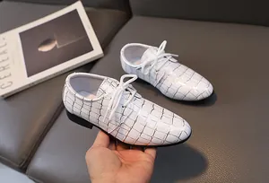 Detail weißer Jungen-Abendschuhe mit goldenem Krokodilmuster und weißen Schnürsenkeln