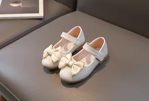 Detailopname van parelwitte Mary Jane schoenen met dubbele strik en gouden randen