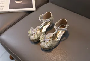 Close-up of golden glittery girl's princess shoes with sparkly rhinestone bow detail