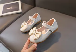Detail van witte prinsessenschoenen voor meisjes met strik en een gouden ketting versiering