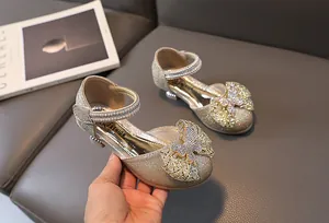 Detail of girls champagne glitter Mary Jane shoes with tulle bow and pearl strap
