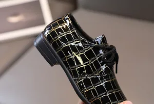 Nahaufnahme der schwarzen Jungen-Halbschuhe mit Kroko-Muster und Schnürsenkeln