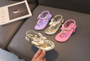 Dettaglio di sandali per bambina con perle e fiocchi in oro, viola, argento e rosa