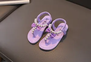 Dettaglio di sandali viola per bambine con perle finte, fiocchi e cinturini elastici