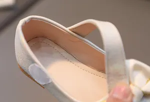 Detailopname van de crème lederen meisjesschoenen met klittenbandsluiting en stikselwerk