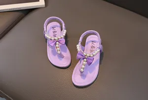 Dettaglio di sandali viola chiaro da bambina con perle, fiocco in raso e cinturino
