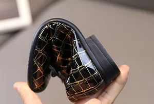 Detail der flexiblen schwarzen Lacklederschuhe mit goldenem Gittermuster für Jungen