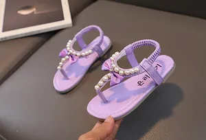 Dettaglio di sandali viola da bambina con perle e fiocco sul cinturino a T