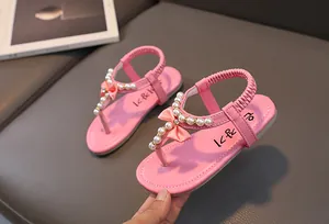 Dettaglio di sandali rosa da bambina con decorazioni di perle e fiocco dolce