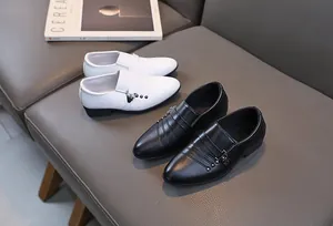Détail de chaussures de cérémonie pour garçons en noir et blanc avec clous et boucles