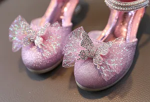 Close-up of pink glitter girls princess shoes with bow and rhinestone butterfly