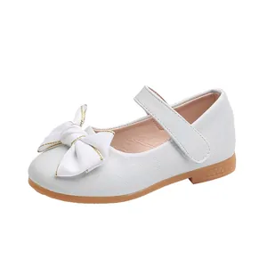 Detail van witte meisjesschoenen met strik, getextureerd leer en antislip rubberen zool