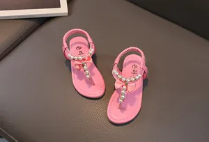 Dettaglio di sandali rosa da bambina con perle e fiocchi di seta su cinturino a T