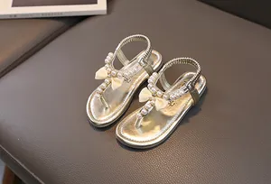 Dettaglio di sandali bambina color champagne con perle, fiocco in seta ed elastico