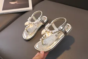 Dettaglio dei sandali dorati per bambina con perle artificiali e fiocco di seta