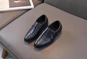 Gros plan de mocassins en cuir noir pour garçons avec boucle en métal et coutures
