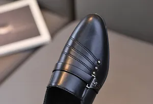 Gros plan de chaussures habillées noires pour garçons avec coutures et clous en métal
