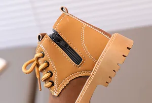 Close-up of children's tan work boots featuring side zipper and durable white stitching