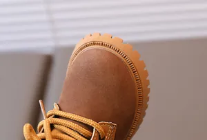 Detail of boys brown suede boots featuring yellow woven laces and anti-slip rubber soles