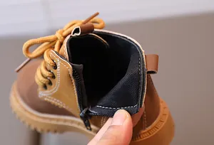 Detail view of children's yellow leather boots showing side zipper and stitching