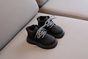 Detail of children's black boots with side zipper, striped laces and fashion round patch