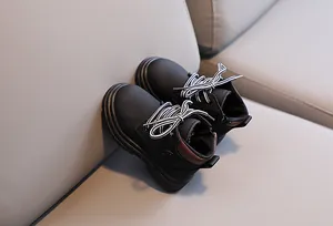 Detail of matte black children's boots with fashion logo and striped laces on a soft base