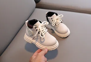 Detail of kids beige leather boots showing side zipper, laces, and anti-slip rubber sole