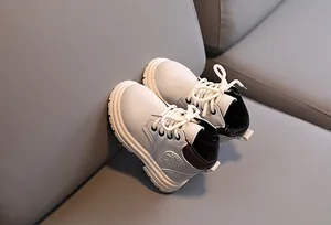 Detail of children's cream lace-up boots showing non-slip rubber sole and side logo patch