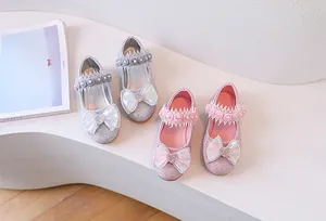 Close-up of glitter girls princess shoes with lace pearl straps and bow details