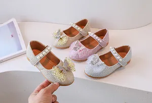 Detalle de zapatos Mary Jane dorados con perlas y lazo brillante para niña pequeña