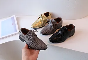 Detail of boys' oxford dress shoes with crocodile texture in gold, grey, and black
