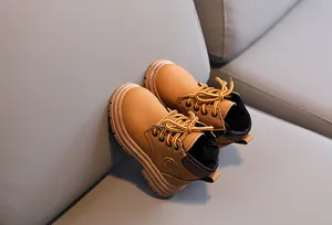Detailed view of khaki leather kids' boots with textured soles and fashion print logo