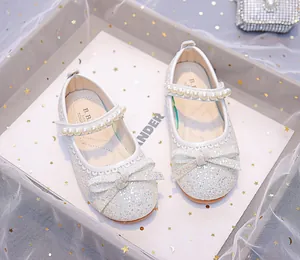 Macro detail of sparkly silver Mary Jane shoes with pearls and bow on sequined material