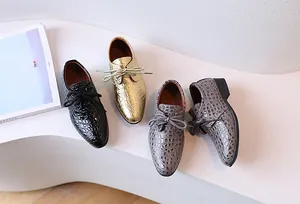 Detailed macro view of gold crocodile embossed leather boys oxfords with lace-up design
