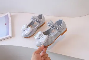 Detailed side view of silver sequin Mary Jane shoes with large bow and pearl accents