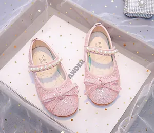 Close-up of pink glitter Mary Jane shoes with pearled strap and sequined bow decoration