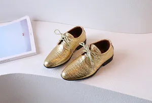 Detail of gold croc-embossed boys' derby shoe with metallic laces on a white background