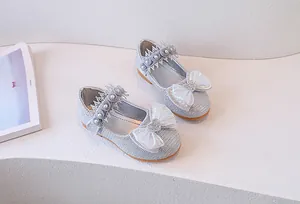 Close-up of girls silver sequin princess shoes with shiny bow and pearl strap detail