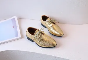Close-up of boys gold oxfords with embossed crocodile pattern and glitter laces