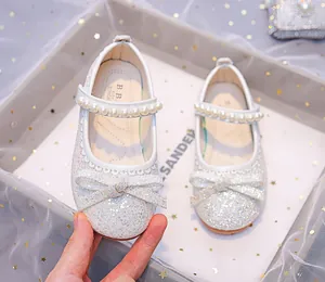Close-up of white sequin girl's princess shoes featuring a pearl strap and bow detail
