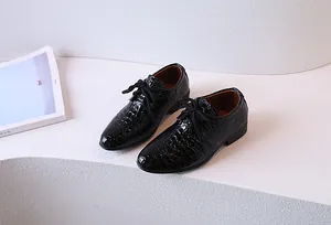 Close-up of black crocodile pattern patent leather boys dress shoes with lace-up detail