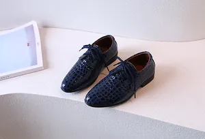 Détail de chaussures habillées à lacets en cuir gaufré crocodile bleu foncé pour garçon
