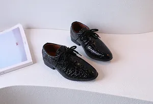 Detail of boys' black patent lace-up shoes featuring embossed crocodile leather texture