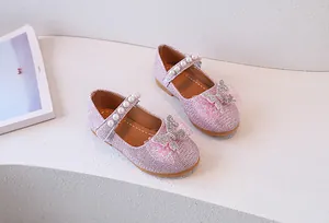 Detalle de zapatos Mary Jane rosa para niña con tira de perlas y lazo de malla brillante