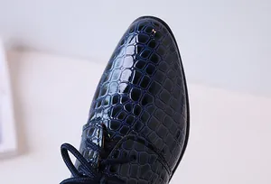 Gros plan sur chaussure habillée bleu foncé pour garçon avec texture croco gaufrée